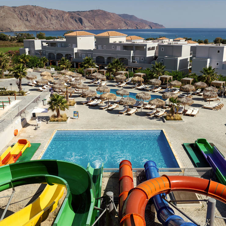 Vantarakis Hotel Collection waterpark with colorful waterslides, large pool, sun loungers, and mountain views near the sea