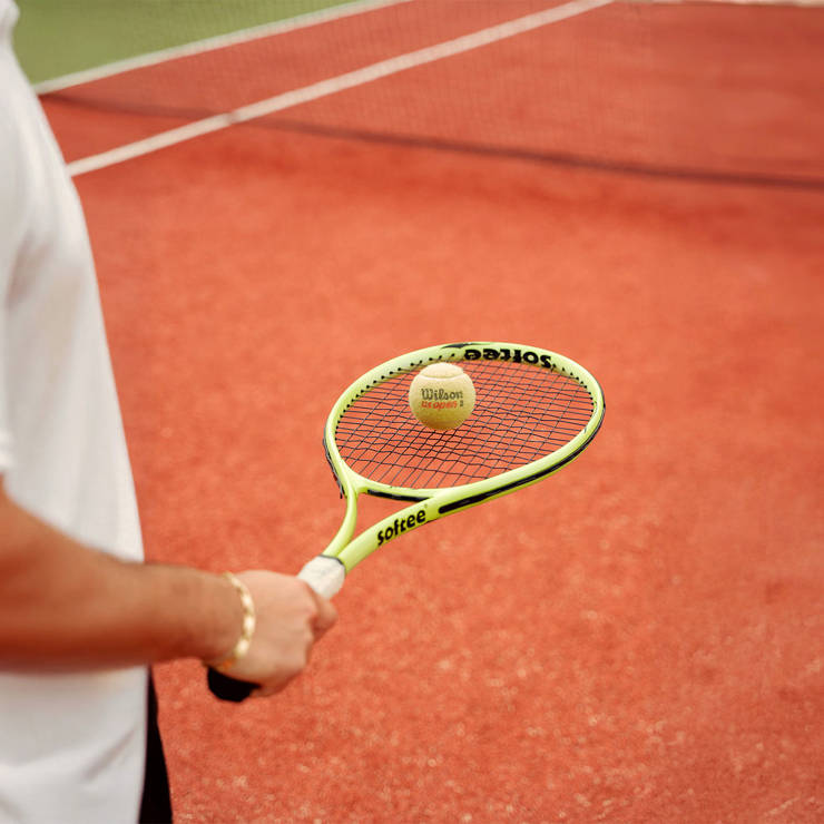 Person holding a tennis racket and ball on a clay court, ready to serve or play