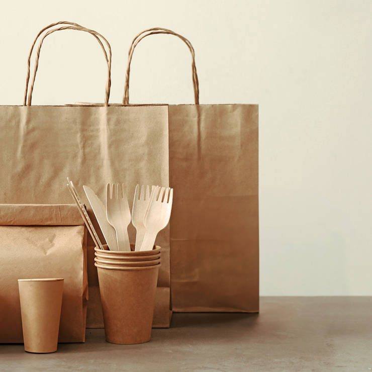 Eco-friendly takeaway packaging and wooden cutlery arranged on a table in a modern, minimalist setting
